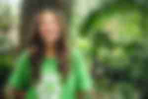 Frau in grünem T-Shirt mit Recycling-Motiv in der Natur